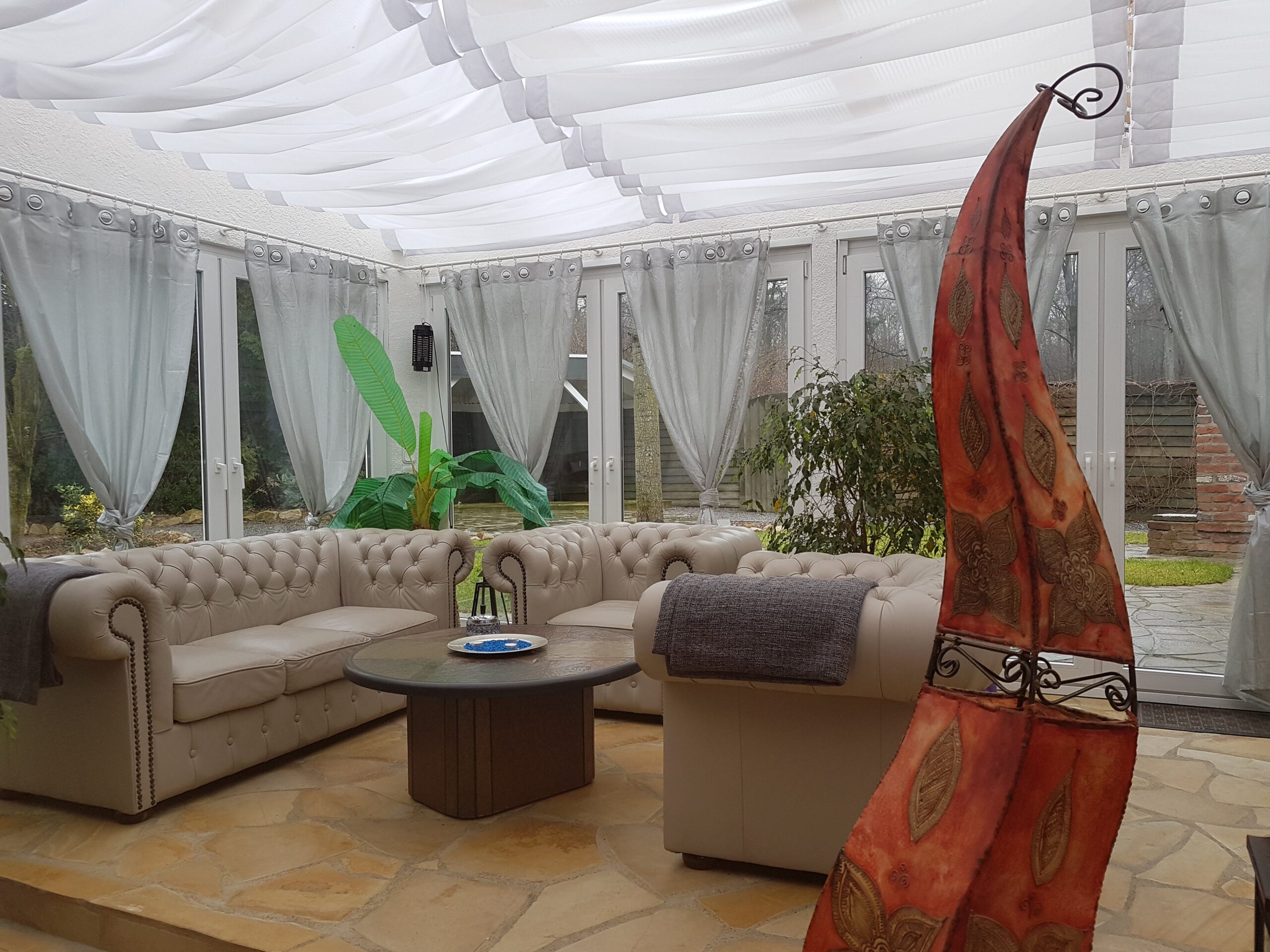 Entspannungsbereich im SM Ferienhaus – Wintergarten mit direktem Zugang zur Terrasse für ungestörte BDSM Ferien